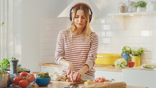 Junge Frau mit Kopfhörern beim Kochen