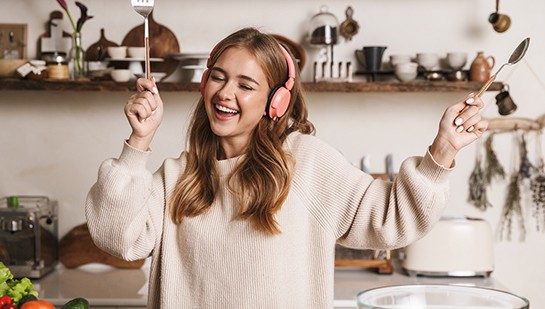 Junge Frau mit Kopfhörern beim Kochen