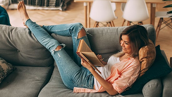 Junge Frau mit Buch auf dem Sofa