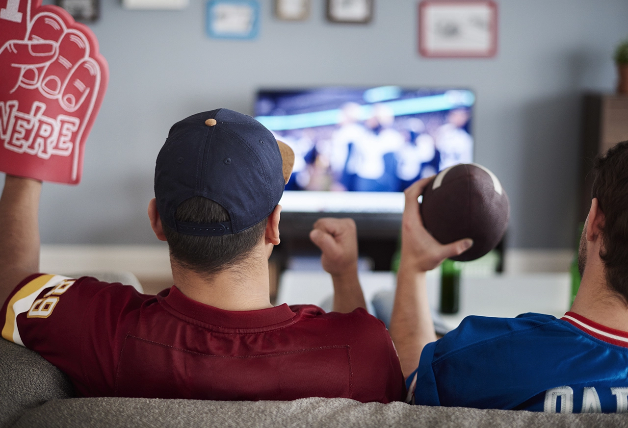 Freunde sitzen zusammen vor dem TV und schauen Football Frau entspannt beim Yoga zu Hause