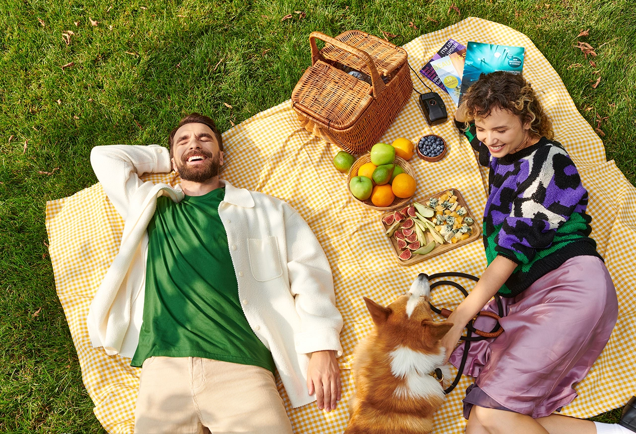 Paar liegt mit Hund auf einer Picknickdecke Frau entspannt beim Yoga zu Hause