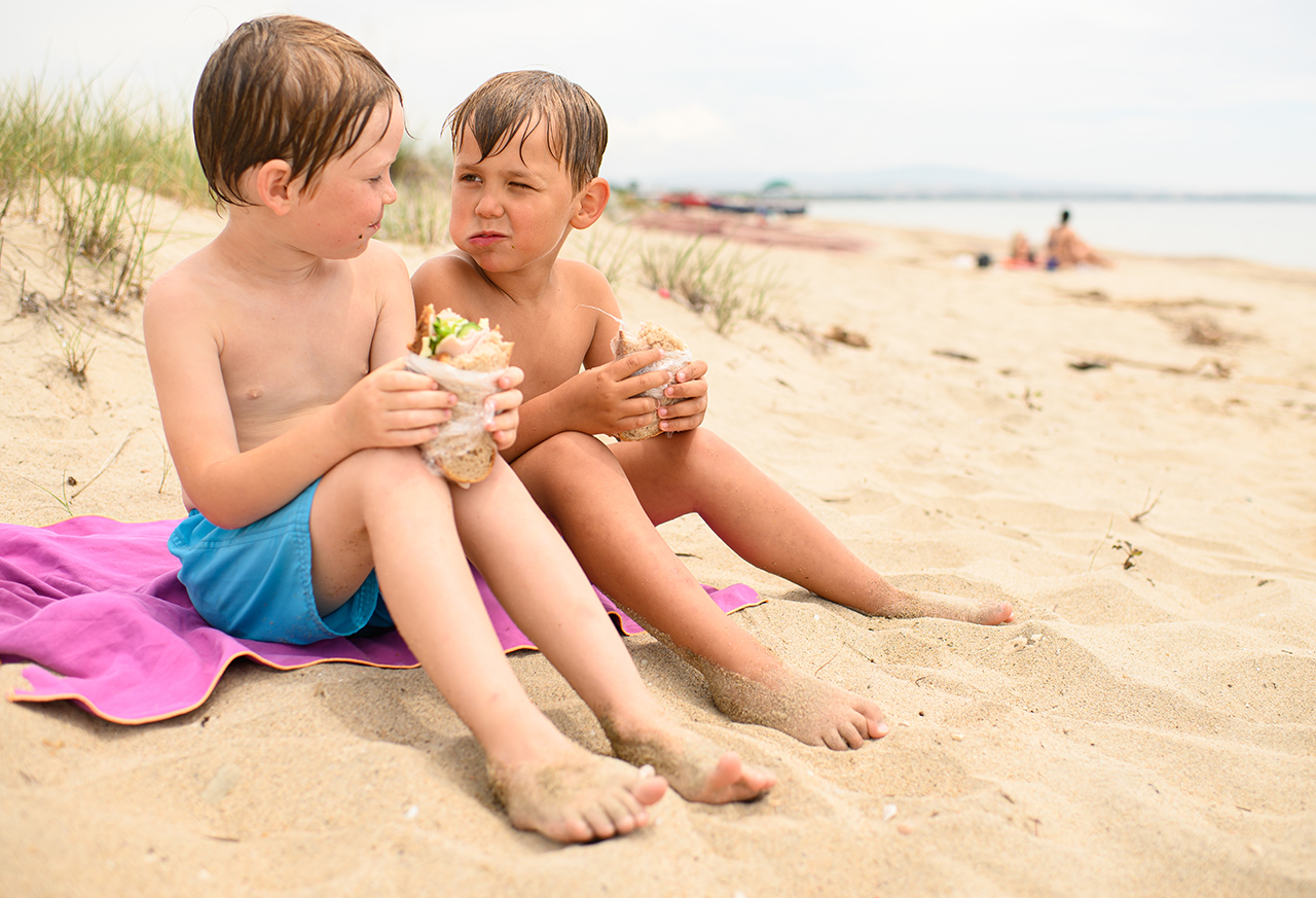 Jungen essen nach dem Schwimmen Sandwiches am Strand Frau entspannt beim Yoga zu Hause