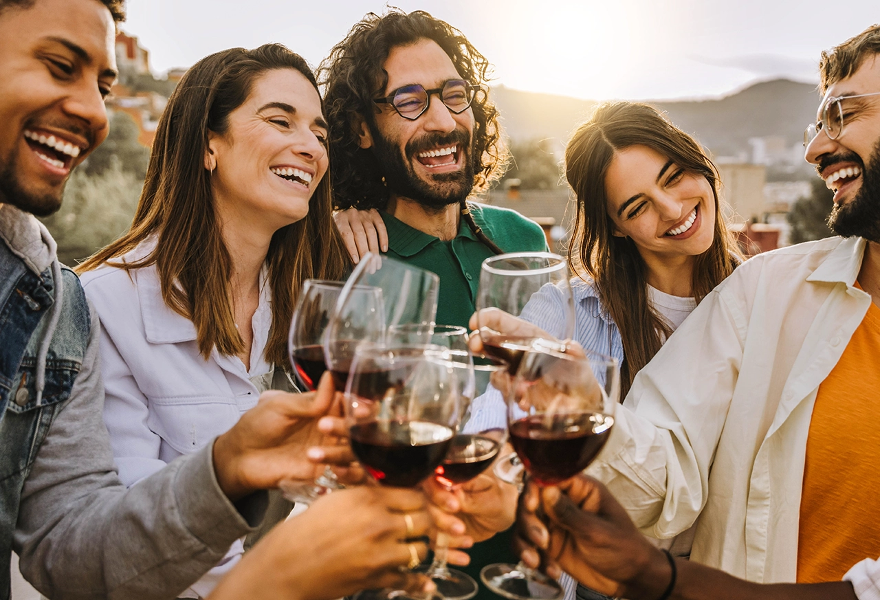 Freunde stoßen gemeinsam mit Wein an Frau entspannt beim Yoga zu Hause