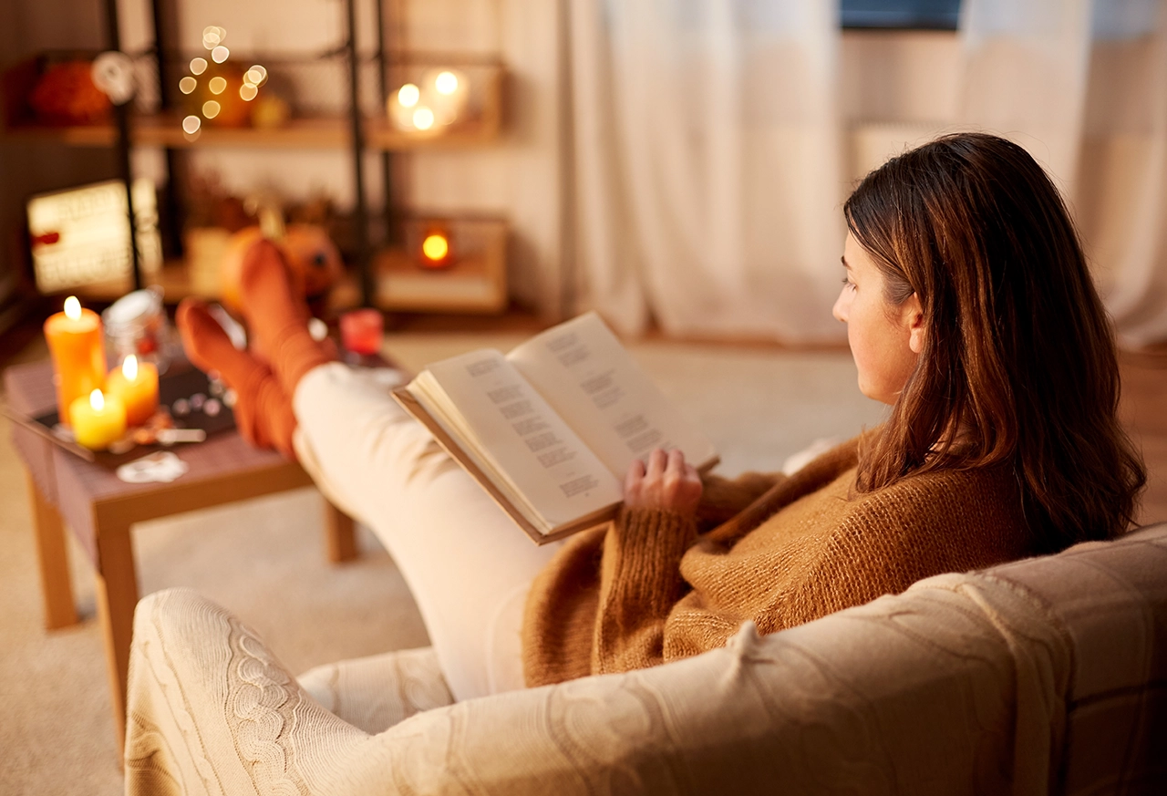 Frau liest auf dem Sofa ein Buch Frau entspannt beim Yoga zu Hause